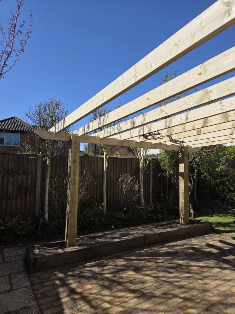 Newly installed timber pergola set over patio and planting beds