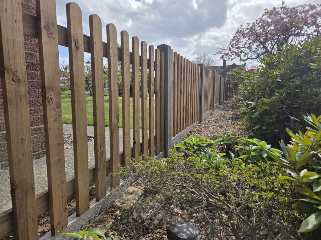 Wooden timber picket fence running alongside planted boarder