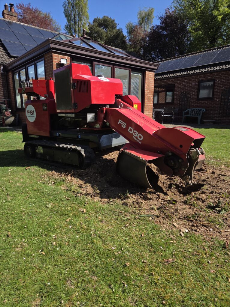 Green grass with soil patch being dug out by red digger