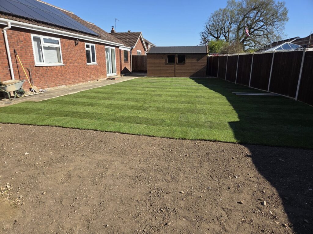 Half completed garden, one half showing level soil, the other showing installed turf